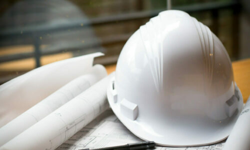 construction concept image helmet rolled blueprints on wooden bo